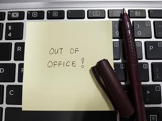 An out-of-office note on desk representing annual leave